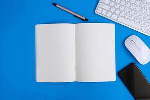 Notebook with pen are on top of office desk table with computer tools and supplies. Top view with copy space, flat lay.  Finance and banking advertising photo