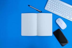 Notebook with pen are on top of office desk table with computer tools and supplies. Top view with copy space, flat lay.  Finance and banking advertising photo