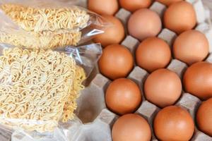 instant noodles and eggs in egg box on background - set of dry food non perishable storage goods in kitchen home or for donations photo
