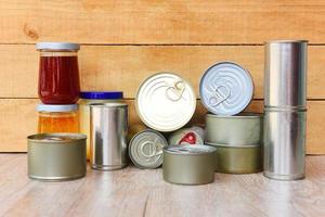 Various canned food in metal cans on wooden background - canned goods non perishable food storage goods in kitchen home or for donations photo