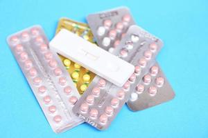 Contraception pills and Pregnancy test on blue background - Birth control contraceptive means prevent pregnancy photo