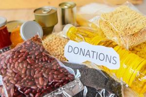 Donations food with canned food on wooden table background pasta canned goods and dry food non perishable with pea beans cooking oil instant noodles macaroni , donate photo