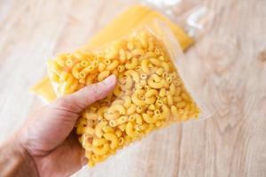 Macaroni in package in hand raw macaroni vermicelli pasta product dry food non perishable food photo