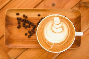 Coffee cup on wooden table in cafe with coffee beans background, Cappuccino or latte coffee, top view. photo