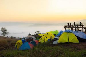 Camping tent area on mountain, tourist tent camping with fog mist landscape sunrise beautiful in winter view outdoor travel. photo