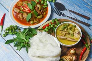 Thai food green curry on soup bowl and red curry on white plate with thai rice noodles ingredient herb vegetable on wooden background - green curry chicken cuisine asian food on the table photo