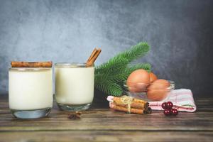 Eggnog delicious holiday drinks like themed parties with cinnamon and nutmeg Traditional Christmas and winter holidays Homemade eggnog in glasses and fresh eggs decorated on the table photo