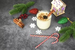 Eggnog delicious holiday drinks like themed parties with cinnamon pine cone and nutmeg for Traditional Christmas and winter holidays Homemade eggnog in glasses candy cane decorated table photo