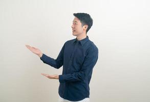 Hombre asiático con la mano apuntando o presentando sobre fondo blanco. foto