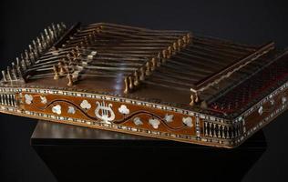 antiguo instrumento musical de cuerda asiático sobre fondo negro con retroiluminación. la similitud del arpa y el salterio foto