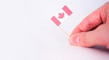 The hand holds the flag of Canada against a gray background. photo