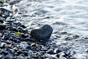 Heart shape stone against background of beach. Summer sunny day. Love, wedding and Valentine day concept. Finding beautiful and interesting stones. Beach vacation photo