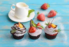 Delicious fresh cakes with berries and white cream on a blue background photo