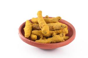 Dry Turmeric roots or barks in clay pot isolated on white background photo