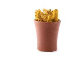 Dry Turmeric roots or barks in clay pot isolated on white background photo