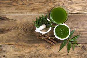 Medicinal Neem leaves in mortar and pestle with neem paste, juice and twigs on wooden background photo