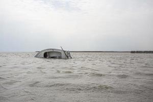 pequeño yate semisumergido en el agua, lago neusiedl, austria. foto