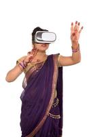 Indian traditional young woman in saree looking though VR device photo