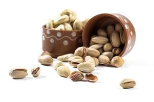 Pistachio and Cashew Nuts in clay pots on white background photo