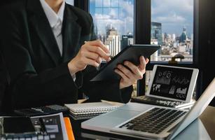 business documents on office table with smart phone and digital tablet and graph financial and woman working photo