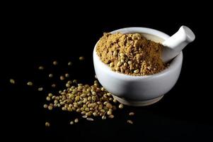 Coriander Powder and seeds with mortar and pestle on black background. photo