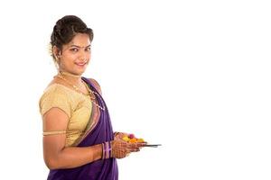 Retrato de una niña tradicional india sosteniendo pooja thali con foto diya, diwali o deepavali con manos femeninas sosteniendo una lámpara de aceite durante el festival de la luz sobre fondo blanco.