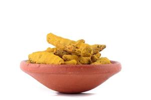 Dry Turmeric roots or barks in clay pot isolated on white background photo