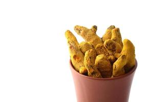 Dry Turmeric roots or barks in clay pot isolated on white background photo
