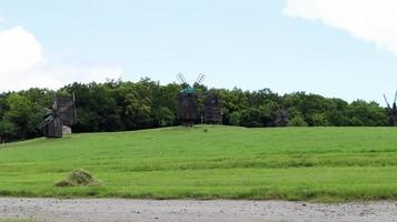 Ukraine, Kiev - June 11, 2020. Old Ukrainian wooden windmills of the XIX century. Summer outdoor landscape. Open-air museum of folk architecture and life, Pirogovo, Ukraine. Tourism and travel. photo