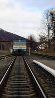 Ucrania, Yaremche - 20 de noviembre de 2019. Tren en la estación sobre un fondo de montañas. vagones de ferrocarril únicos en el andén de la ciudad de yaremche. Antiguo tren de pasajeros diesel. estación de ferrocarril. foto