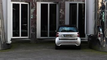 Dusseldorf, Germany - February 28, 2020. Photo of a parking lot near a building with one small gray car. brand of cars of a particularly small class. city double and very economical mini car.