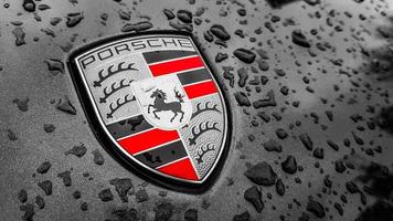 Ukraine, Kiev - March 27, 2020. Porsche logo close up on a black car with raindrops. Hood emblem of a sports car. copy space, editorial photography. German car exhibition on the street. photo