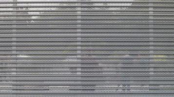 Close-up of a gray metal mesh as a security measure in front of a closed shopping center. Closed gates at the entrance to the store that impede the entry or destruction of places for criminals. photo