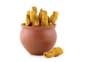 Dry Turmeric roots or barks in clay pot isolated on white background photo