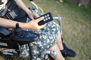 Asian lady woman patient on electric wheelchair with joystick and remote control at nursing hospital ward, healthy strong medical concept photo