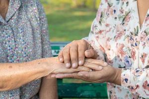 Caregiver holding hands Asian senior or elderly old lady woman patient with love, care, encourage and empathy at nursing hospital ward, healthy strong medical concept photo