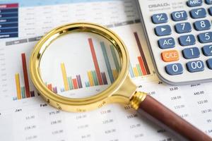 Magnifying glass on charts graphs paper. Financial development, Banking Account, Statistics, Investment Analytic research data economy, Stock exchange trading, Business office company meeting concept. photo