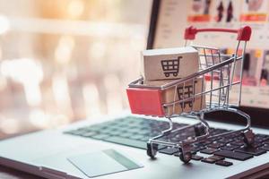 Shopping online. Credit card and cardboard box with a shopping cart logo in a trolley on laptop keyboard. Shopping service on The online web. offers home delivery photo