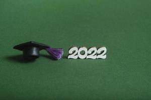 Graduation cap and numbers 2022 on green background, closeup with copy space. Medical education concept. photo