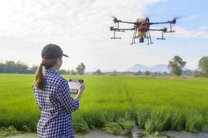 joven agricultor inteligente que controla la fumigación de fertilizantes y pesticidas con drones sobre tierras de cultivo, innovaciones de alta tecnología y agricultura inteligente foto