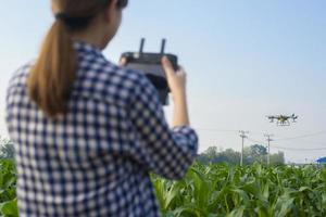 Young smart farmer controlling drone spraying fertilizer and pesticide over farmland,High technology innovations and smart farming photo