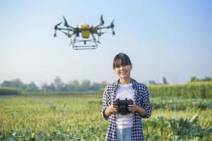 Young smart farmer controlling drone spraying fertilizer and pesticide over farmland,High technology innovations and smart farming photo