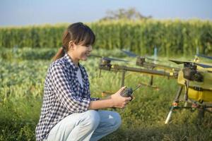 Young smart farmer controlling drone spraying fertilizer and pesticide over farmland,High technology innovations and smart farming photo