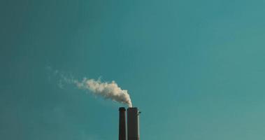Smoke coming out of a coal power plant chimney against blue sky, slow motion video