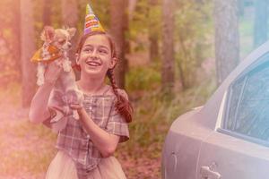 Girl 11 years old with a chihuahua dog in a birthday hat in the forest. Super mood of birthday girl. photo