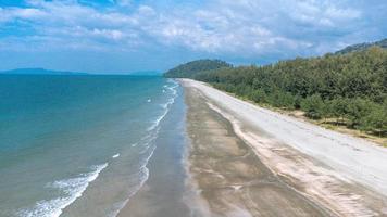 hermosa playa negra con olas marinas en el parque nacional laem son, ranong, tailandia. la playa del mar y los pinos están a mitad de camino en la imagen panorámica aérea. foto