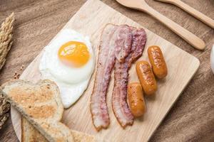 breakfast set with sauaage bacon omelette on the table wooden photo