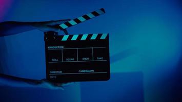 Hand holds empty film making clapperboard on color background in studio photo