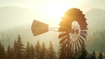 Typical Old Windmill turbine in forest at sunset photo