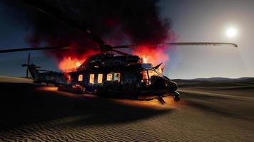 burned military helicopter in the desert at sunset photo